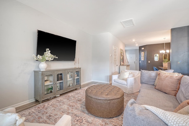 living room with baseboards, a notable chandelier, and wood finished floors