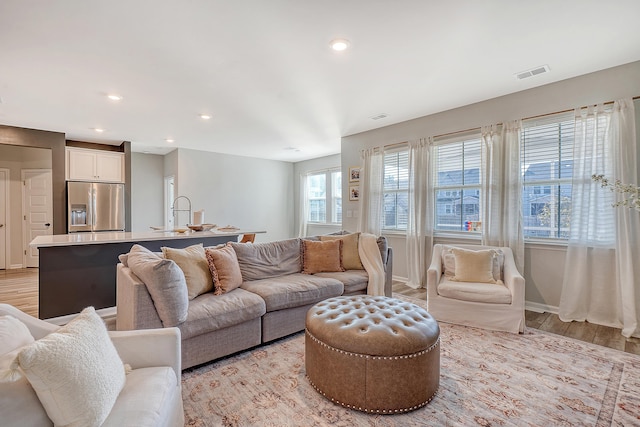 living room with light wood-style floors, baseboards, visible vents, and recessed lighting