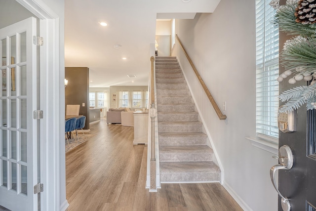 stairs with baseboards, wood finished floors, and recessed lighting