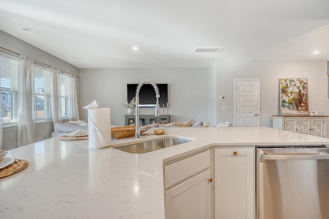 kitchen with a sink, visible vents, open floor plan, light stone countertops, and dishwasher