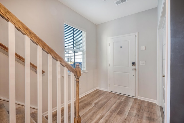 foyer entrance featuring baseboards, visible vents, light wood finished floors, and stairs