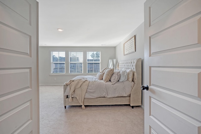 bedroom with baseboards and light colored carpet