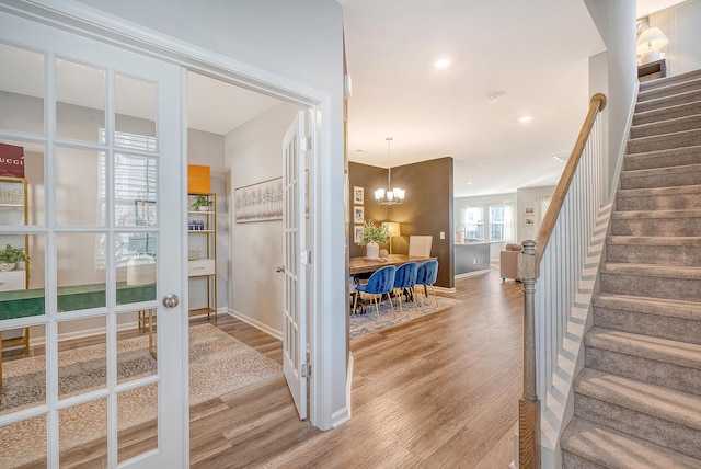 interior space with stairs, baseboards, wood finished floors, and an inviting chandelier