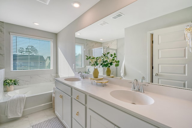 bathroom featuring marble finish floor, visible vents, a sink, and a garden tub