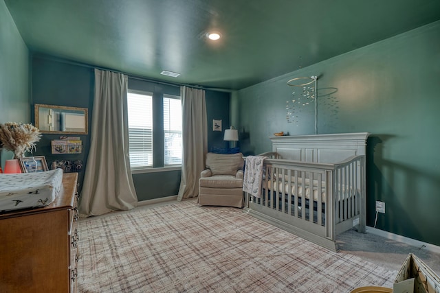 carpeted bedroom featuring a crib, baseboards, and visible vents