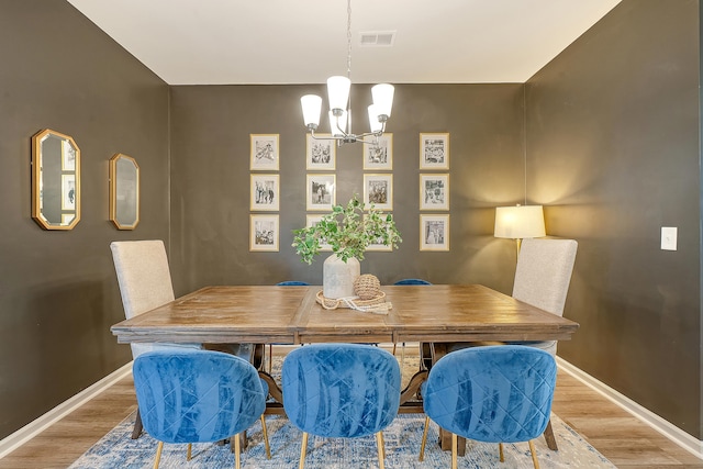 dining space with baseboards, wood finished floors, visible vents, and a notable chandelier