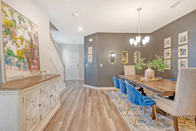 dining area with baseboards, visible vents, stairs, light wood-style floors, and a notable chandelier