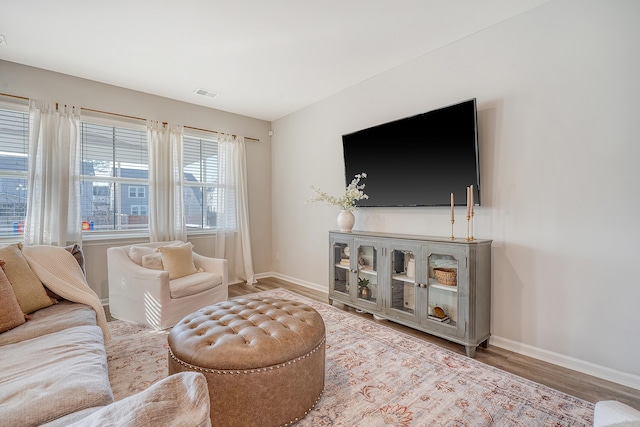 living area featuring visible vents, baseboards, and wood finished floors