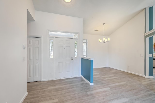 entrance foyer with vaulted ceiling, light hardwood / wood-style floors, and a chandelier