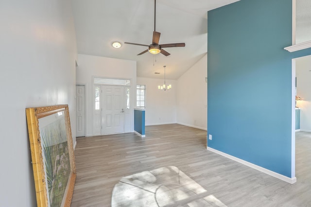 foyer entrance with ceiling fan with notable chandelier, high vaulted ceiling, and light wood-type flooring