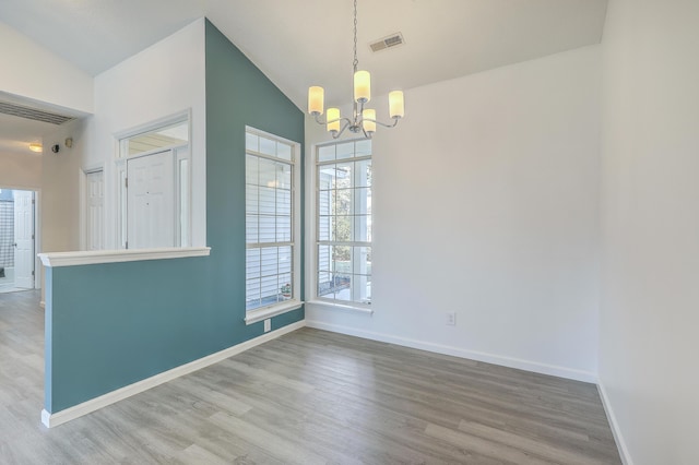 unfurnished dining area featuring hardwood / wood-style flooring, vaulted ceiling, and a notable chandelier