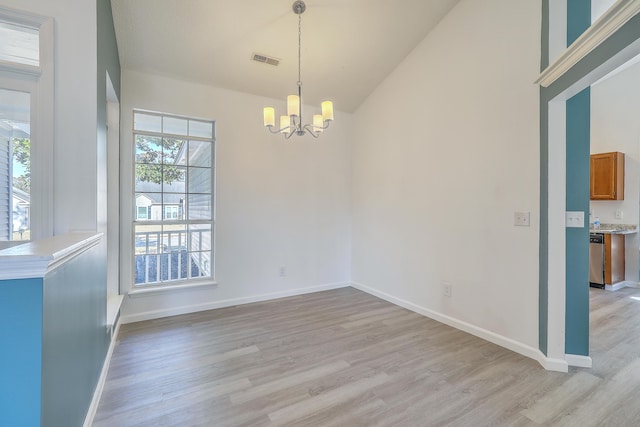 unfurnished room featuring an inviting chandelier, vaulted ceiling, and light hardwood / wood-style floors