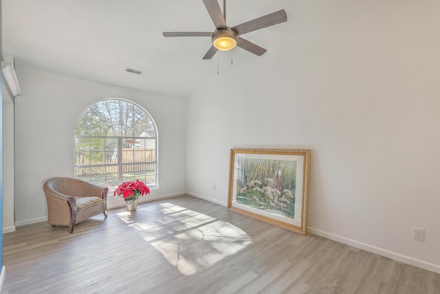 living area featuring lofted ceiling, light hardwood / wood-style floors, and ceiling fan