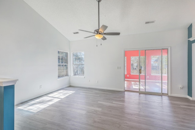 spare room with hardwood / wood-style flooring, ceiling fan, lofted ceiling, and a textured ceiling