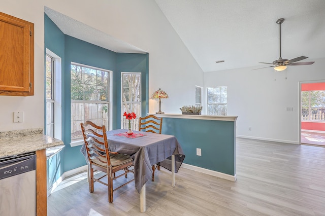 dining space featuring vaulted ceiling, ceiling fan, a textured ceiling, and light wood-type flooring