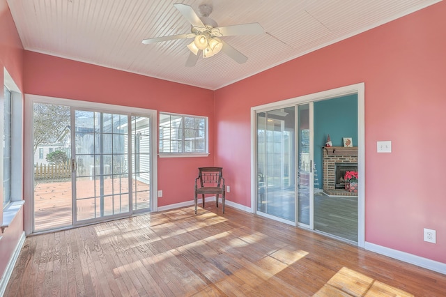 unfurnished room with a fireplace, wood-type flooring, and ceiling fan