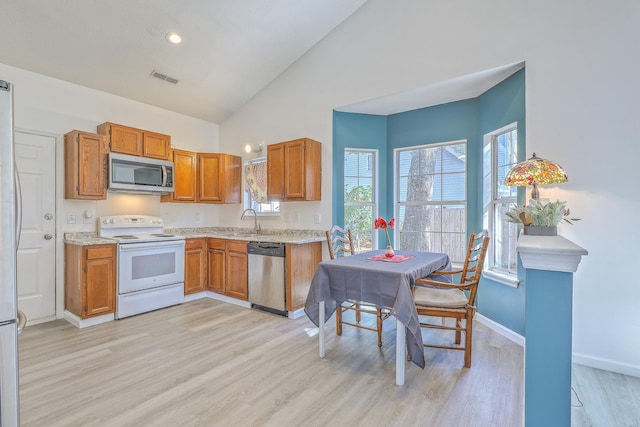 kitchen featuring stainless steel appliances, high vaulted ceiling, sink, and light wood-type flooring