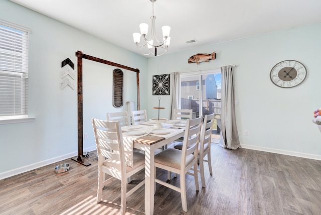 dining space with wood-type flooring and a notable chandelier