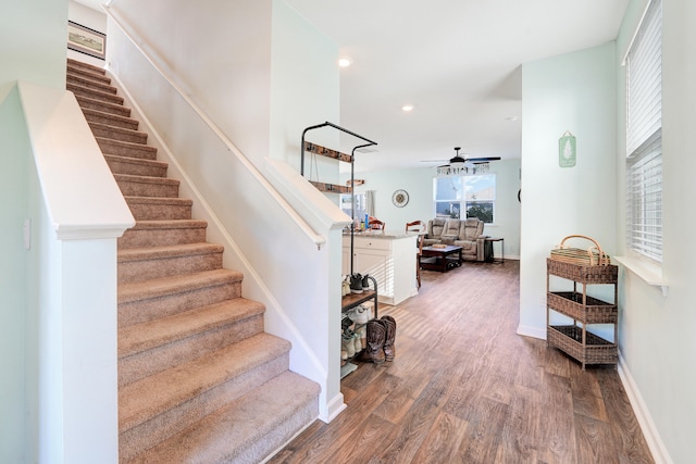 staircase with ceiling fan and wood-type flooring