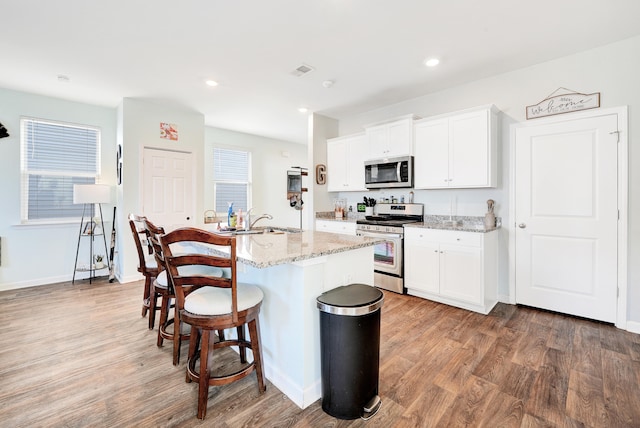 kitchen featuring white cabinets, dark wood-type flooring, appliances with stainless steel finishes, and an island with sink