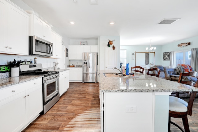 kitchen with a center island with sink, white cabinetry, wood-type flooring, and stainless steel appliances