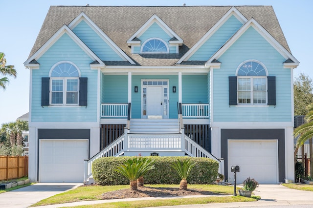 coastal inspired home featuring a porch, driveway, and a garage