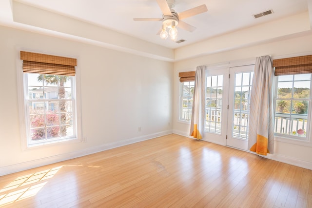 empty room with baseboards, a healthy amount of sunlight, and light wood-style floors
