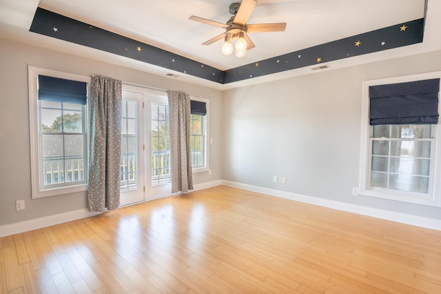 spare room with baseboards, a raised ceiling, visible vents, and a healthy amount of sunlight