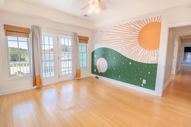 empty room featuring baseboards, ceiling fan, wood finished floors, and visible vents