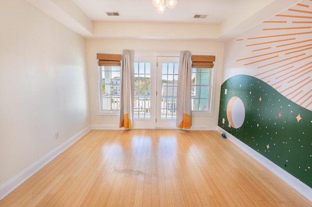 unfurnished room with baseboards, wood finished floors, and visible vents