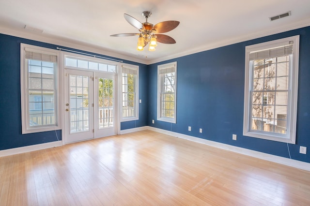 spare room with crown molding, ceiling fan, baseboards, wood finished floors, and visible vents