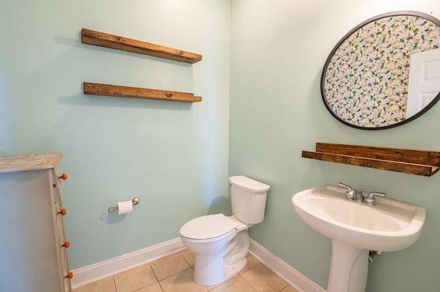 bathroom featuring baseboards, tile patterned flooring, and toilet