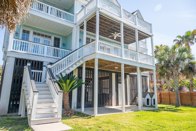 rear view of house with fence, a balcony, stairs, a patio area, and a yard
