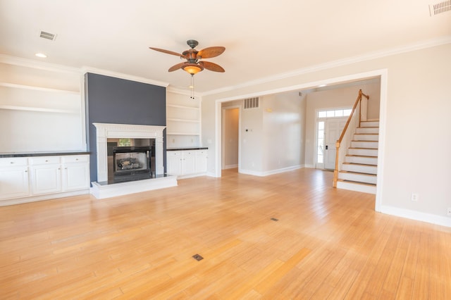 unfurnished living room with visible vents, baseboards, built in shelves, a ceiling fan, and a premium fireplace