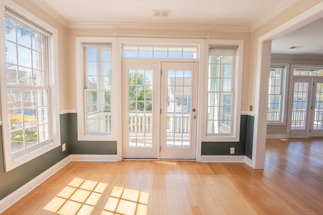doorway with crown molding, baseboards, and wood finished floors