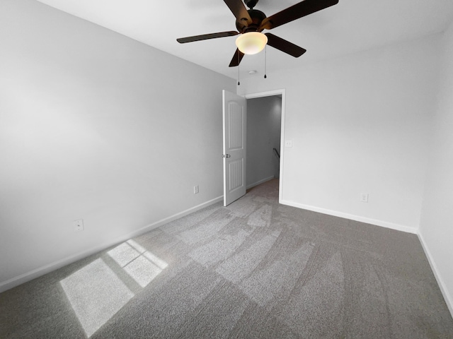 carpeted spare room with ceiling fan and baseboards