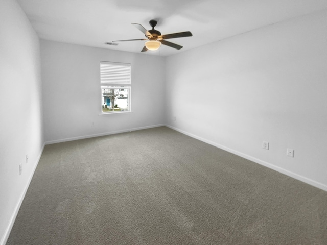 carpeted empty room with visible vents, a ceiling fan, and baseboards