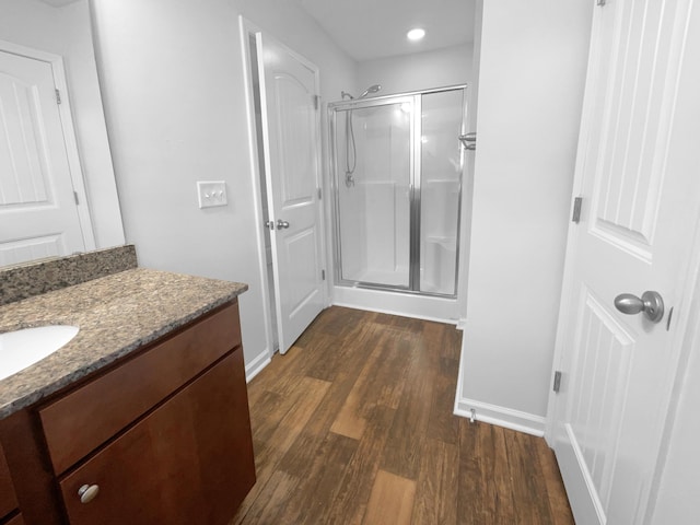 bathroom featuring vanity, a shower stall, wood finished floors, and baseboards