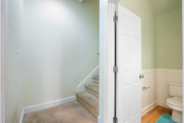 bathroom featuring toilet, wood finished floors, wainscoting, and baseboards