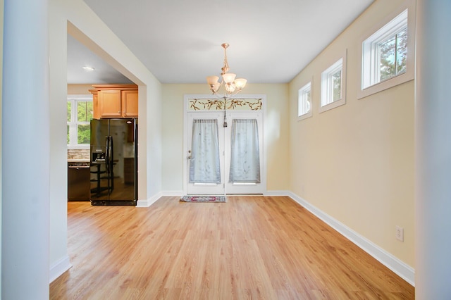 foyer entrance featuring a chandelier, light wood-type flooring, and a healthy amount of sunlight
