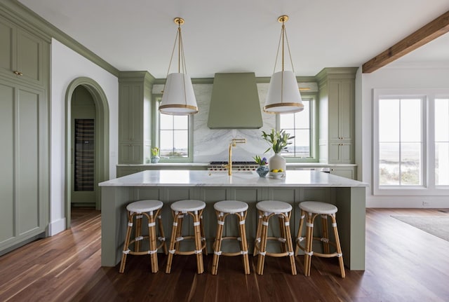 kitchen featuring a breakfast bar area, dark hardwood / wood-style floors, an island with sink, and pendant lighting