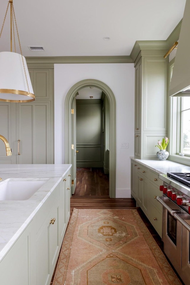 kitchen with dark wood-type flooring, custom exhaust hood, sink, light stone countertops, and range with two ovens