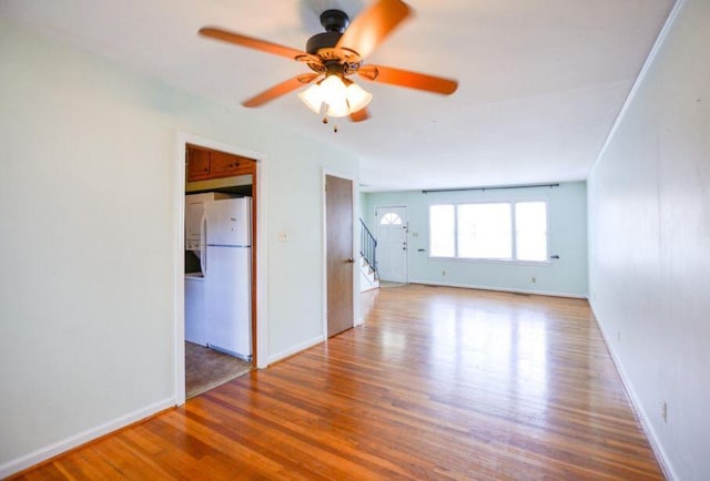 unfurnished room with baseboards, wood finished floors, and a ceiling fan