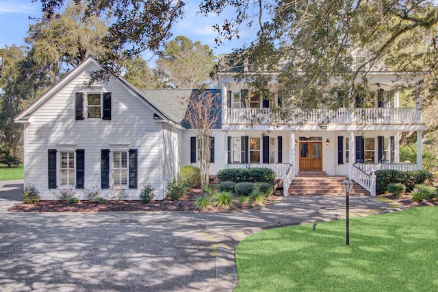 view of front of property with covered porch, a front yard, and a balcony