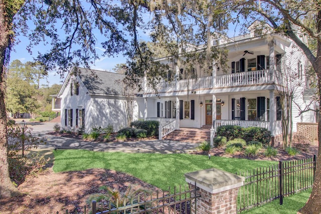 view of front facade with ceiling fan, a porch, a front yard, and a balcony