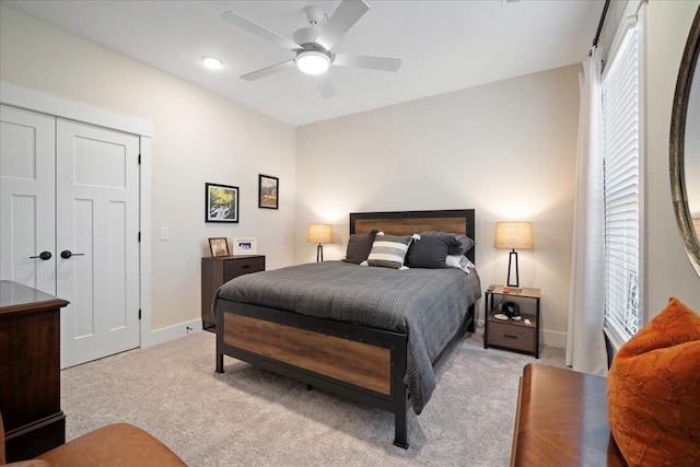 bedroom featuring ceiling fan, light colored carpet, and a closet