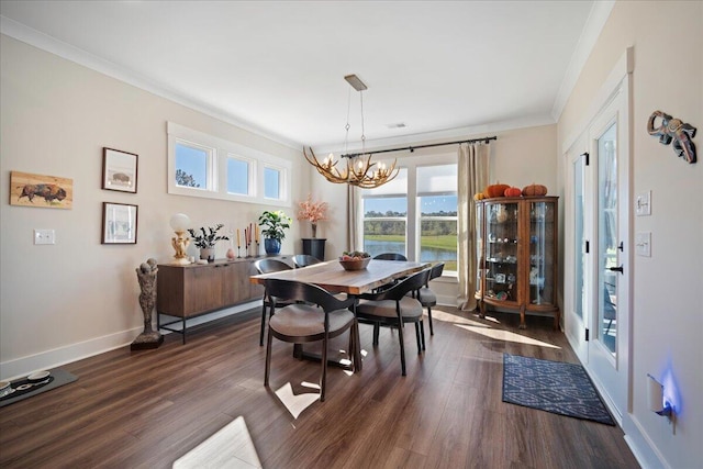 dining area with a chandelier, crown molding, dark wood-type flooring, baseboards, and a water view