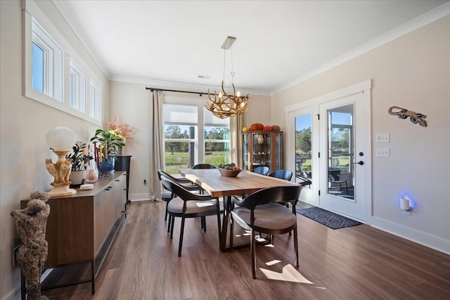 dining area with a chandelier, dark wood-style flooring, baseboards, and crown molding