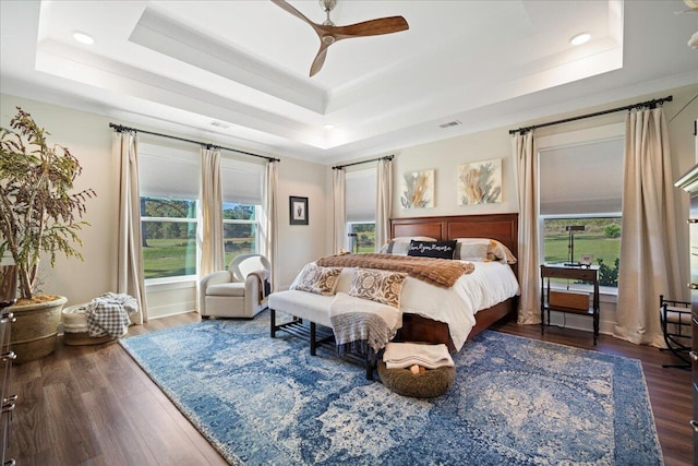 bedroom with a raised ceiling, wood finished floors, recessed lighting, a ceiling fan, and ornamental molding