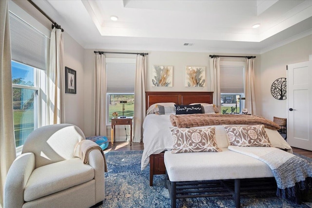 bedroom featuring a tray ceiling, wood finished floors, ornamental molding, and recessed lighting